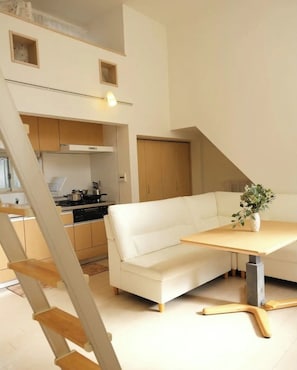 Eine moderne Küche mit weißen Schränken, einem weißen Sofa und einem Holzes Esstisch.