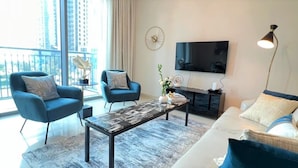 A modern living room with a sofa, two armchairs, a coffee table, and a TV. - Luxury Dubai Creek Harbour Waterfront Apartment (Dubai)