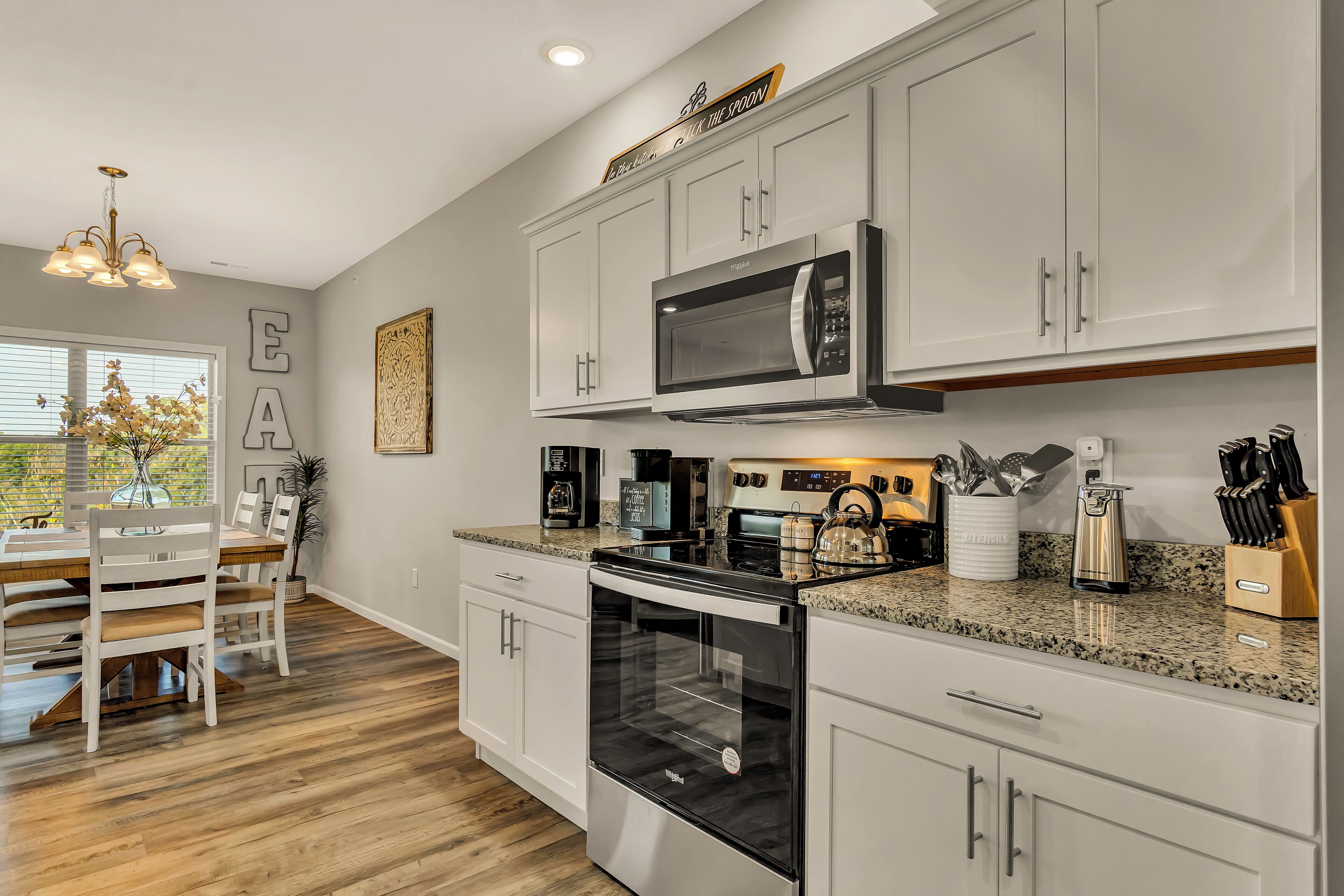 A modern kitchen with white cabinets, stainless steel appliances, and a granite countertop.