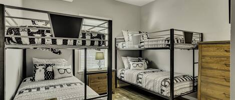 Ein Schlafsaalzimmer mit Etagenbetten, Holoszilloschen und einem Deckenventilator.