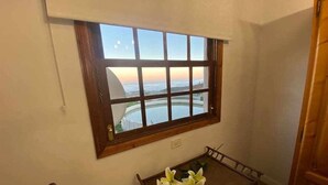 A room with a large window overlooking a scenic view, a small table with a vase of flowers, and a wooden chair.