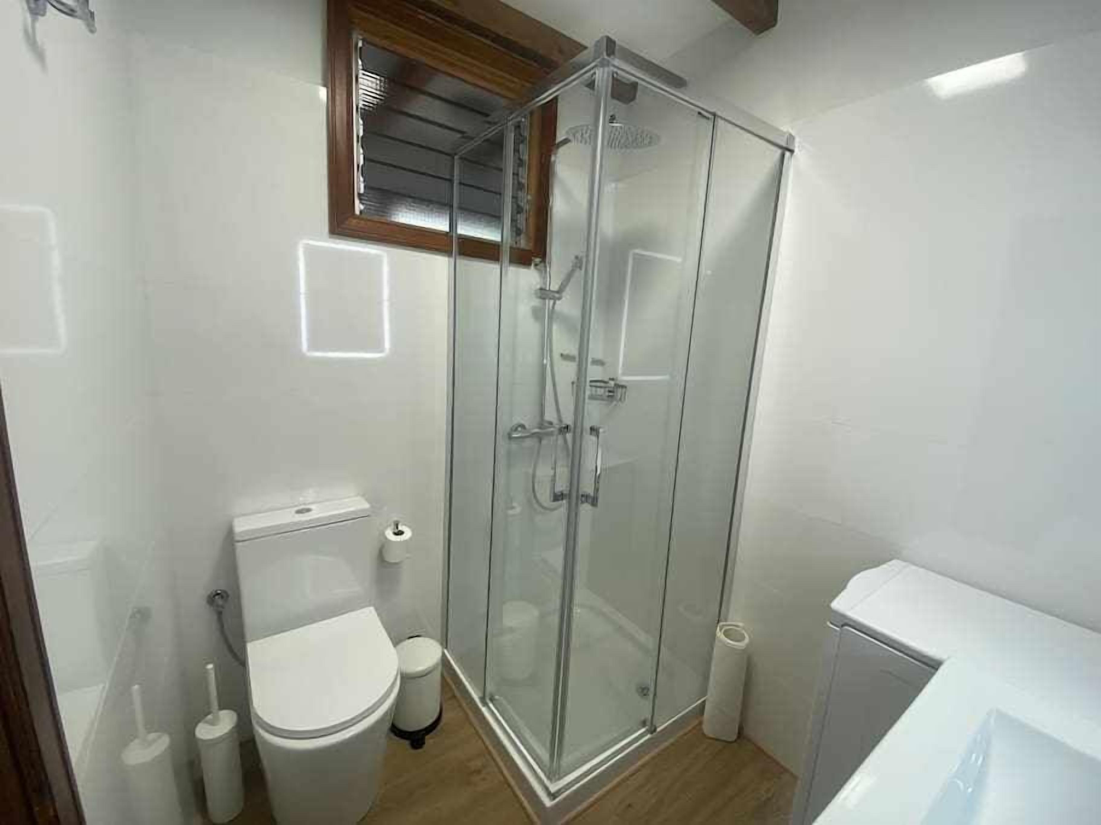 Un baño pequeño y moderno con ducha envuelta en vidrio, inodoro y bidé.