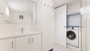 Un baño moderno con lavamanos, espejo y lavadora.