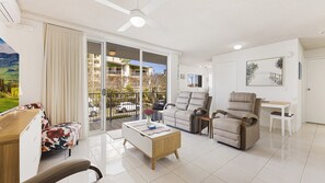 A modern living room with a sofa, two armchairs, a coffee table, and a dining area with a table and chairs.