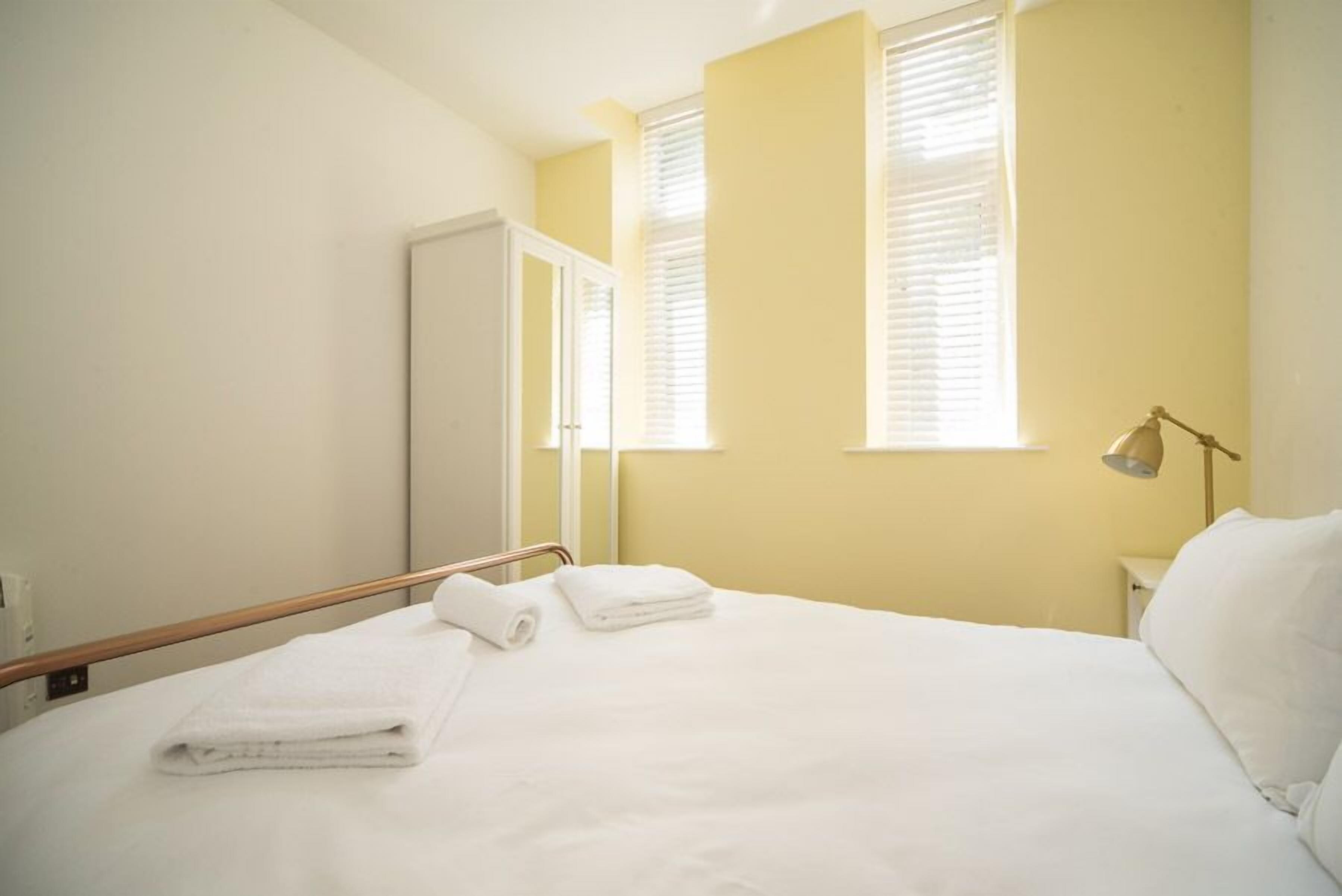 Ein Hotelzimmer mit Bett, Nachttischlampe und einem Fenster mit Jalousien.
