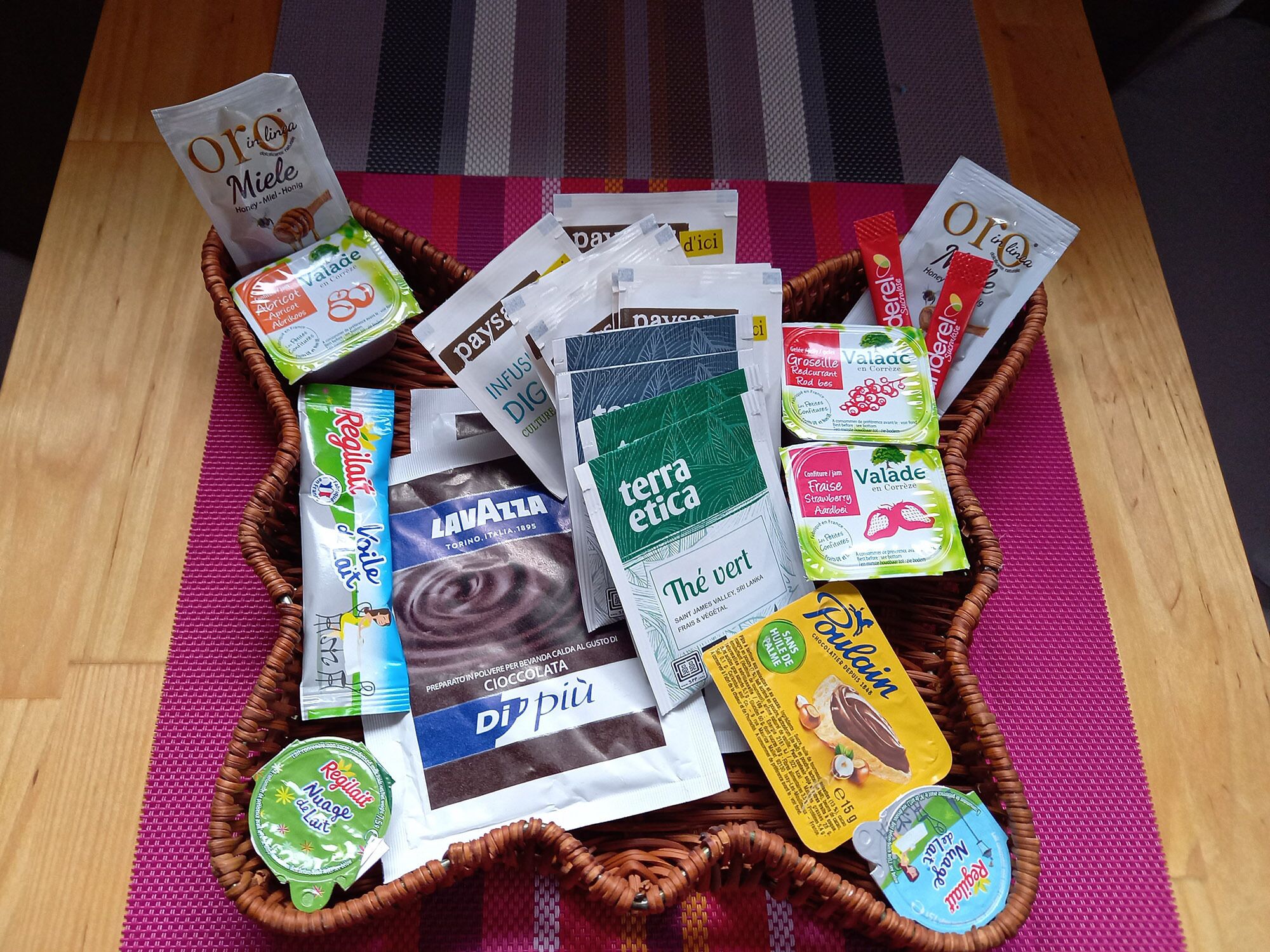 Een mand gevuld met diverse etenswaren en verpakkingen, waaronder snacks en zuiverproducten.