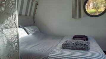 Un dormitorio con cama, almohadas, una ventana con vistas y un separador decorativo.