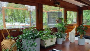 Une pièce dotée de grandes fenêtres, de murs en bois et de différentes plantes en pot.