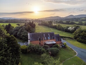 A house with a large garden and a view of the surrounding countryside. - Owlbury Hall Barn (Montgomery)