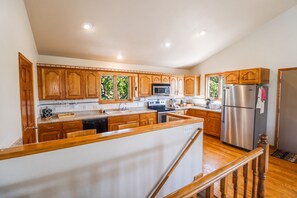 A kitchen with wooden cabinets, stainless steel appliances, and a wooden staircase.
