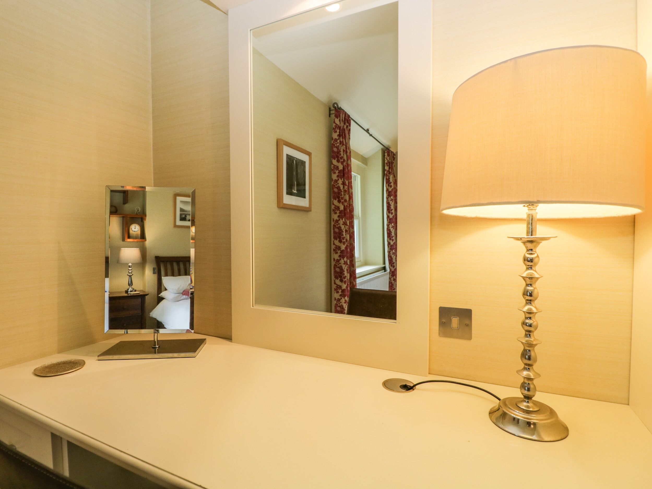 Bagno d'albergo con lavandino, specchio e lampada a parete.