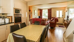 Amplia sala de estar con una mesa de comedor, sillas, un conjunto de sofá y una cocina equipada.