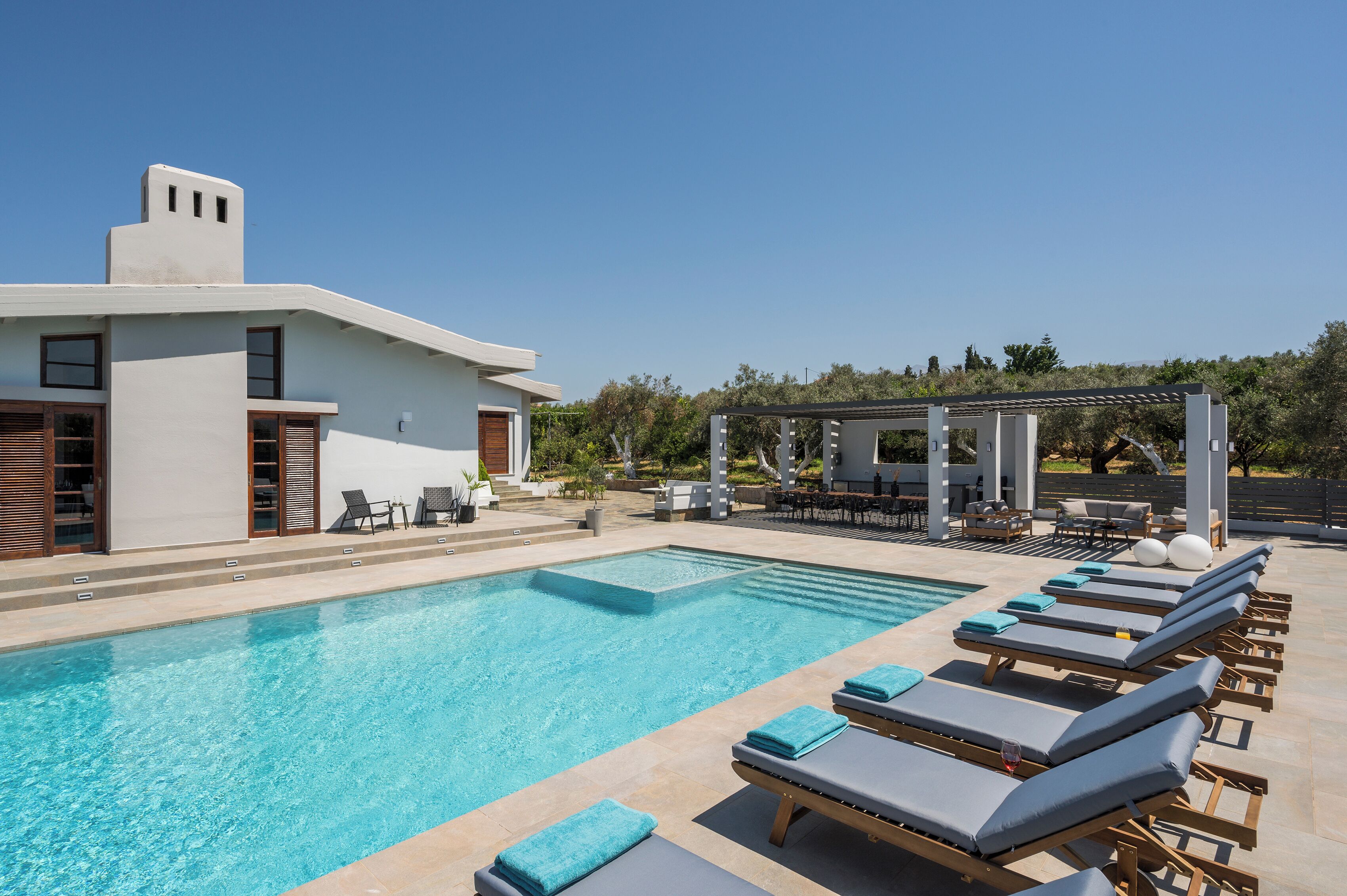 Une piscine avec des chaises longues et une pergola.