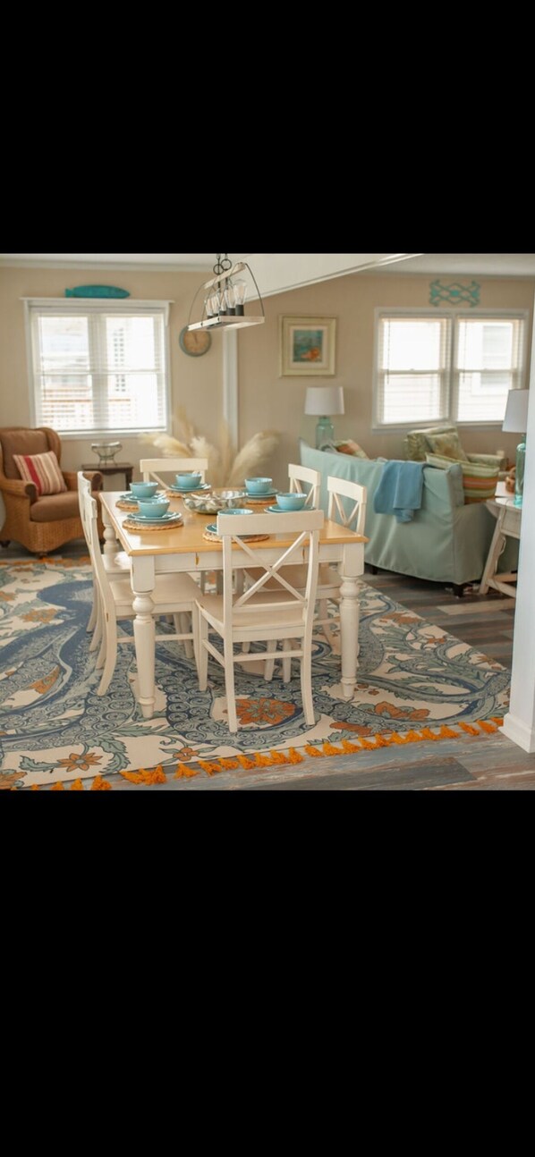 A dining area with a wooden table and white chairs, a patterned rug, and a blue and white color scheme.