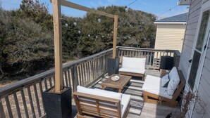 A wooden deck with a sofa, a coffee table, and a potted plant. - Comfortable and clean beach cottage convenient access to the beach. (Kitty Hawk)