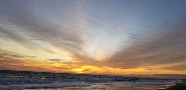 A beach scene with waves and a sunset.