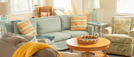 A living room with a sofa, armchair, and a round coffee table.