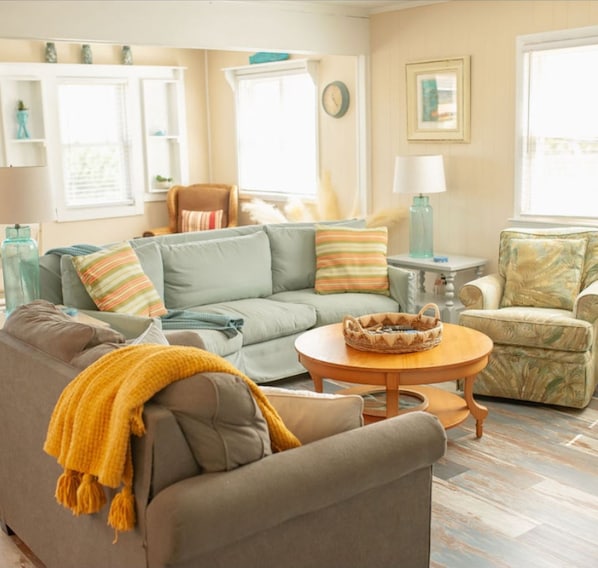 A living room with a sofa, armchair, and a round coffee table. - Comfortable and clean beach cottage convenient access to the beach. (Kitty Hawk)