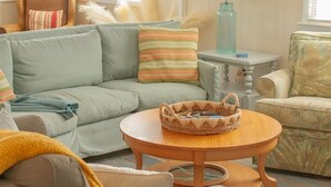 A cozy living room with a sofa, armchair, and a round coffee table. - Comfortable and clean beach cottage convenient access to the beach. (Kitty Hawk)