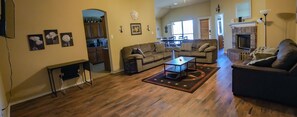 A spacious living room with a wooden floor, a sofa, a coffee table, and a fireplace.