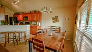 A dining area with a wooden table and chairs, a kitchen with wooden cabinets, and a chandelier.