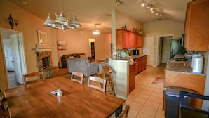 Ein großzügiges Wohnzimmer mit Kamin, ein Essbereich mit Holztisch sowie eine Küche mit Holzschränken und einer Granitarbeitsplatte.