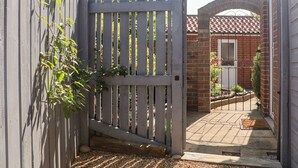 A wooden gate leading to a brick house with a tiled roof and a small garden area. - Pond Farm View (Saltburn-by-the-Sea)