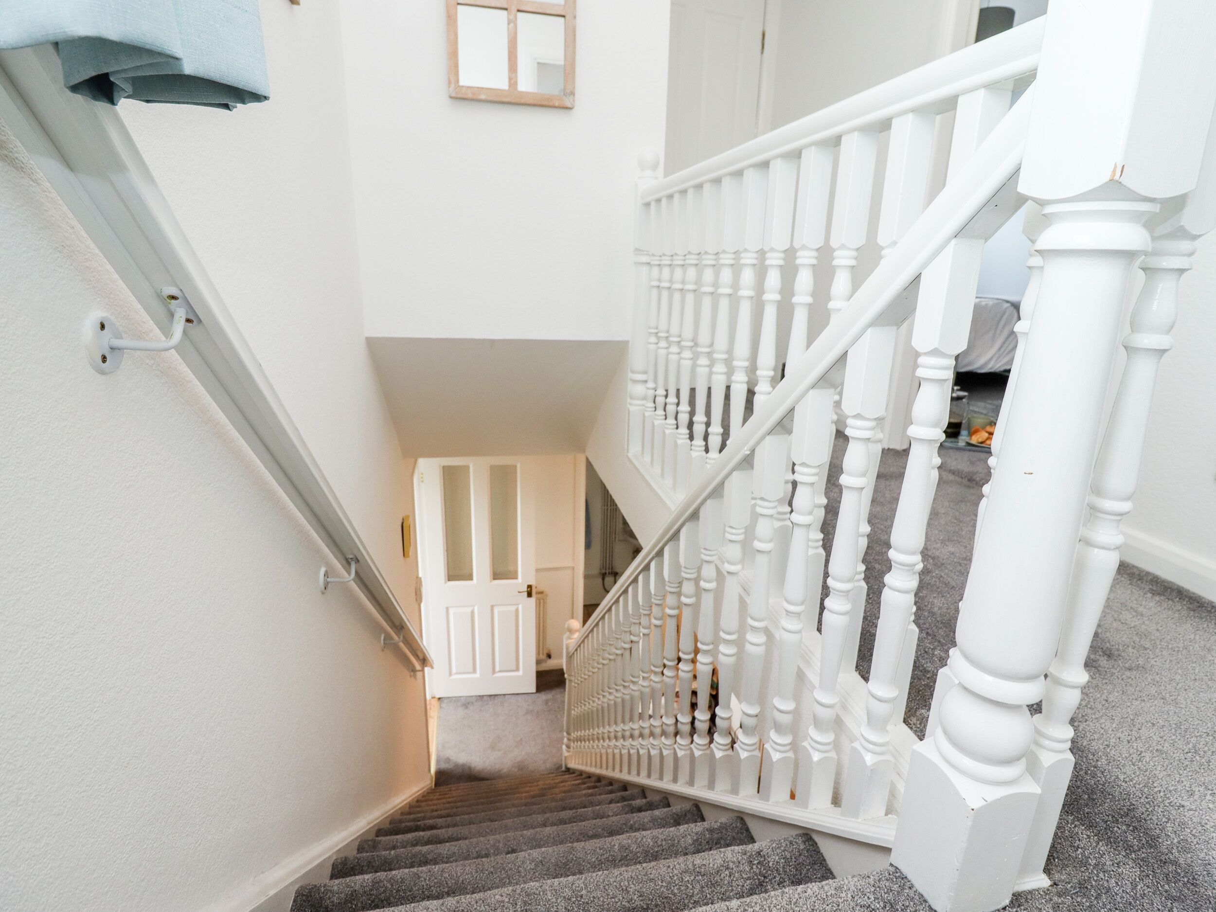 A staircase with white balusters and a carpeted landing.