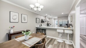 A modern kitchen with a central island, bar stools, and a dining area with a wooden table and chairs. - Relaxing Home close the Battery/Mins to Everything (Smyrna)