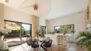 Una cocina moderna con una mesa de comedor de cristal, sillas negras y un ventanal grande.