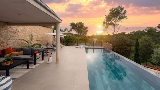 Un área de piscina al aire libre con un muro de piedra, un sofá y una silla de descanso.