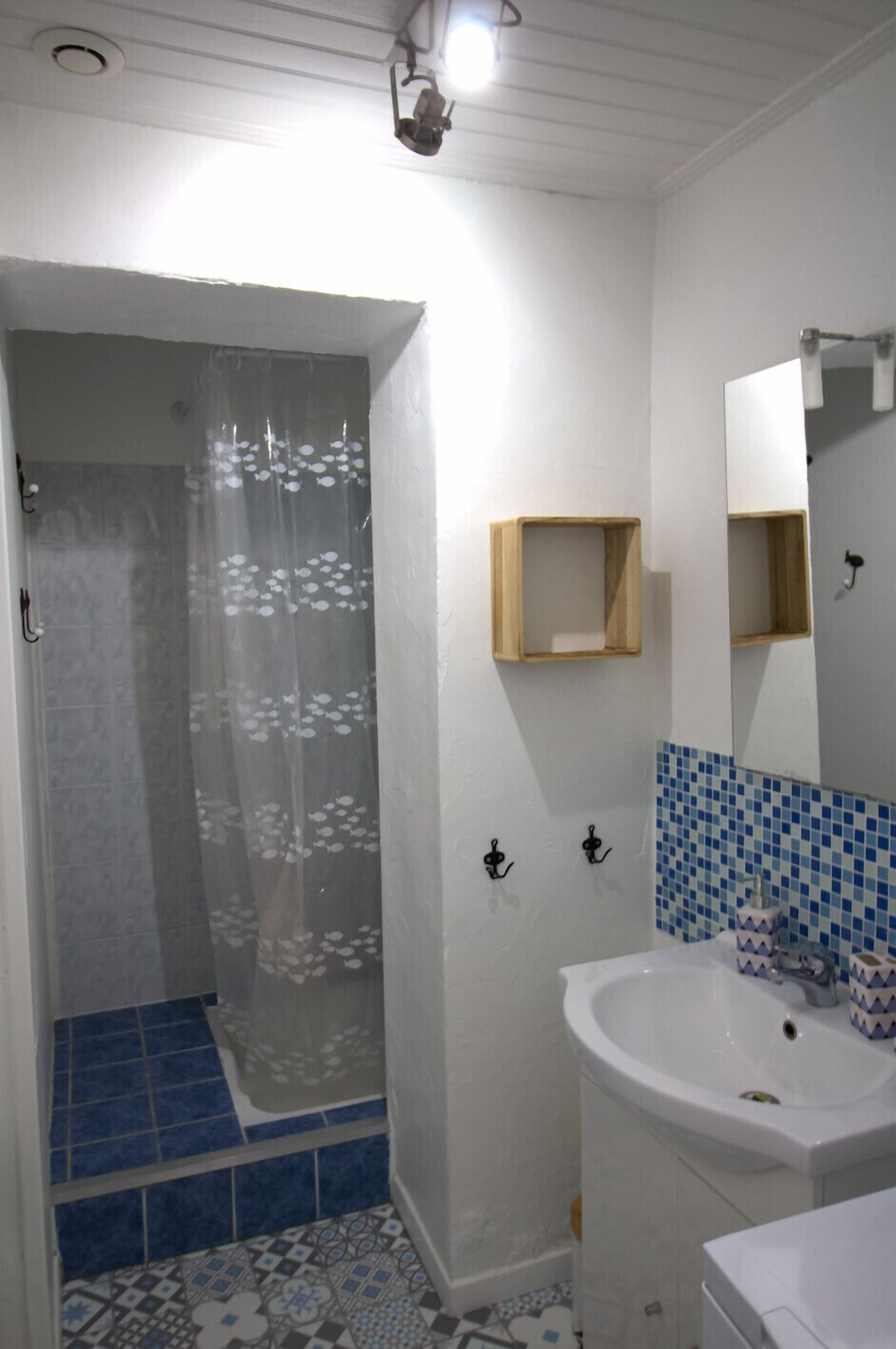 Een badkamer met een douche, wastafel en spiegel.