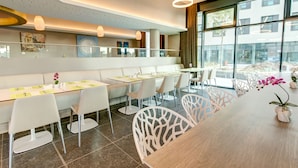 Un comedor moderno con sillas blancas, una mesa de madera y vistas al exterior a través de amplios ventanales.