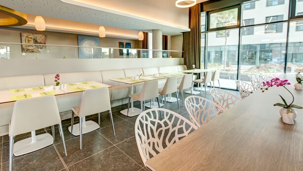 Un comedor moderno con sillas blancas, una mesa de madera y vistas al exterior a través de amplios ventanales.