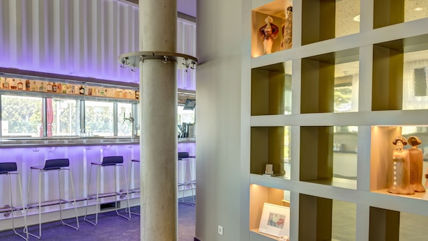 Un interior moderno con una zona de bar, asientos y estantes de exhibición.