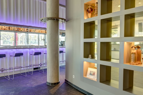 Un interior moderno con una zona de bar, asientos y estantes de exhibición.