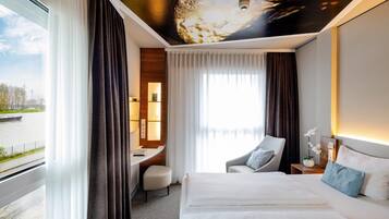 Habitación de hotel con cama, escritorio, silla y vistas al exterior.