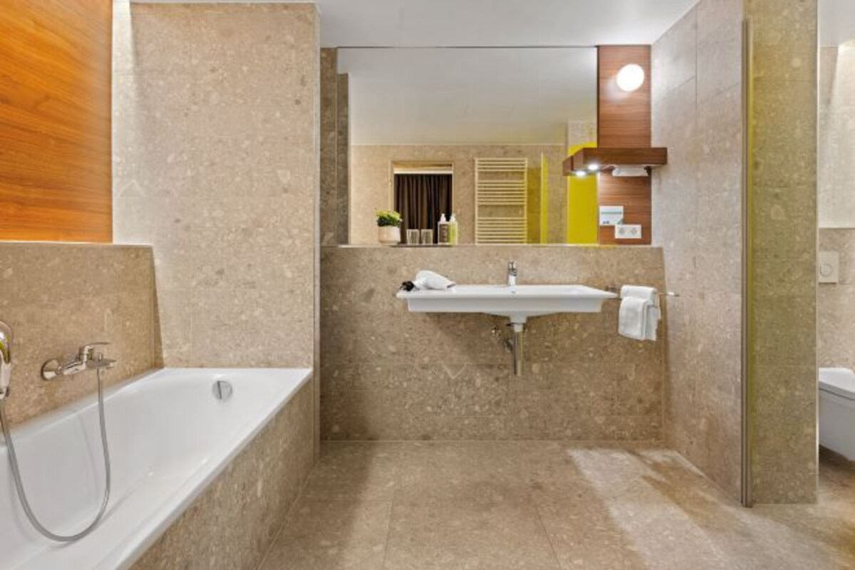 Un baño moderno con bañera, lavamanos y espejo.