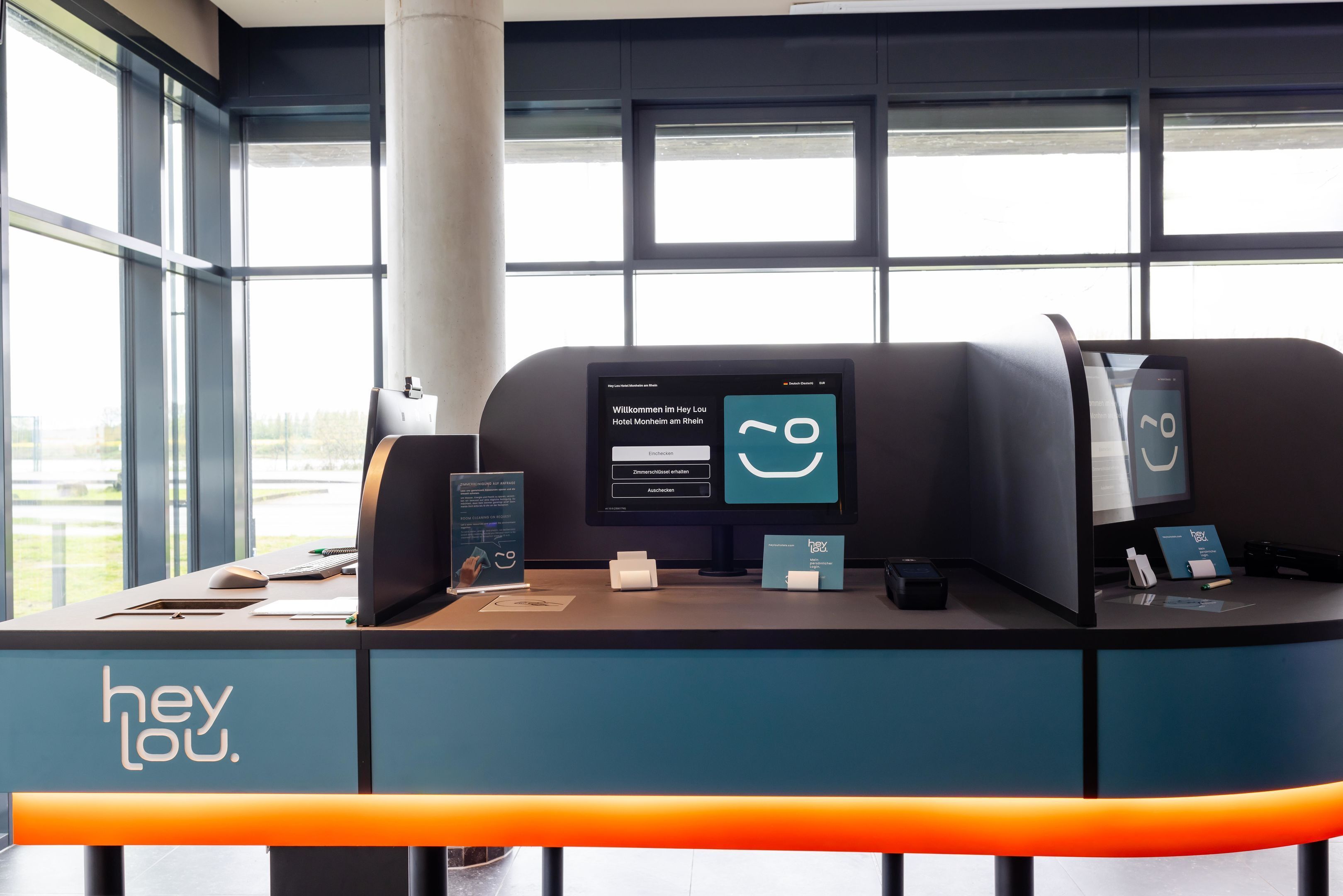 En modern receptionsdisk med en digital skärm, en bordstelefon och en skylt med texten ”hej”.