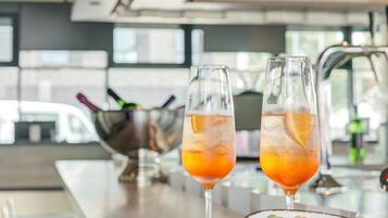 Dos vasos de bebida de naranja sobre una barra con un cuenco de frutos secos al lado.