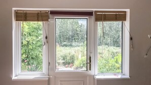 Une pièce avec une porte blanche et trois fenêtres équipées de stores en bois.