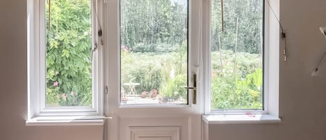 Een kamer met een witte deur en drie ramen met houten zonwering.