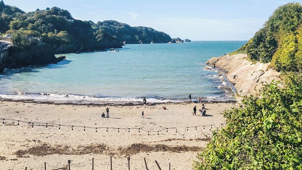Une plage offrant une vue dégagée sur la mer, avec des falaises rocheuses et une rive sablonneuse.