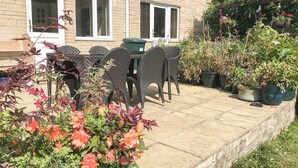 Un espace patio aménagé avec du mobilier d’extérieur, un mur en briques et des plantes en pot.