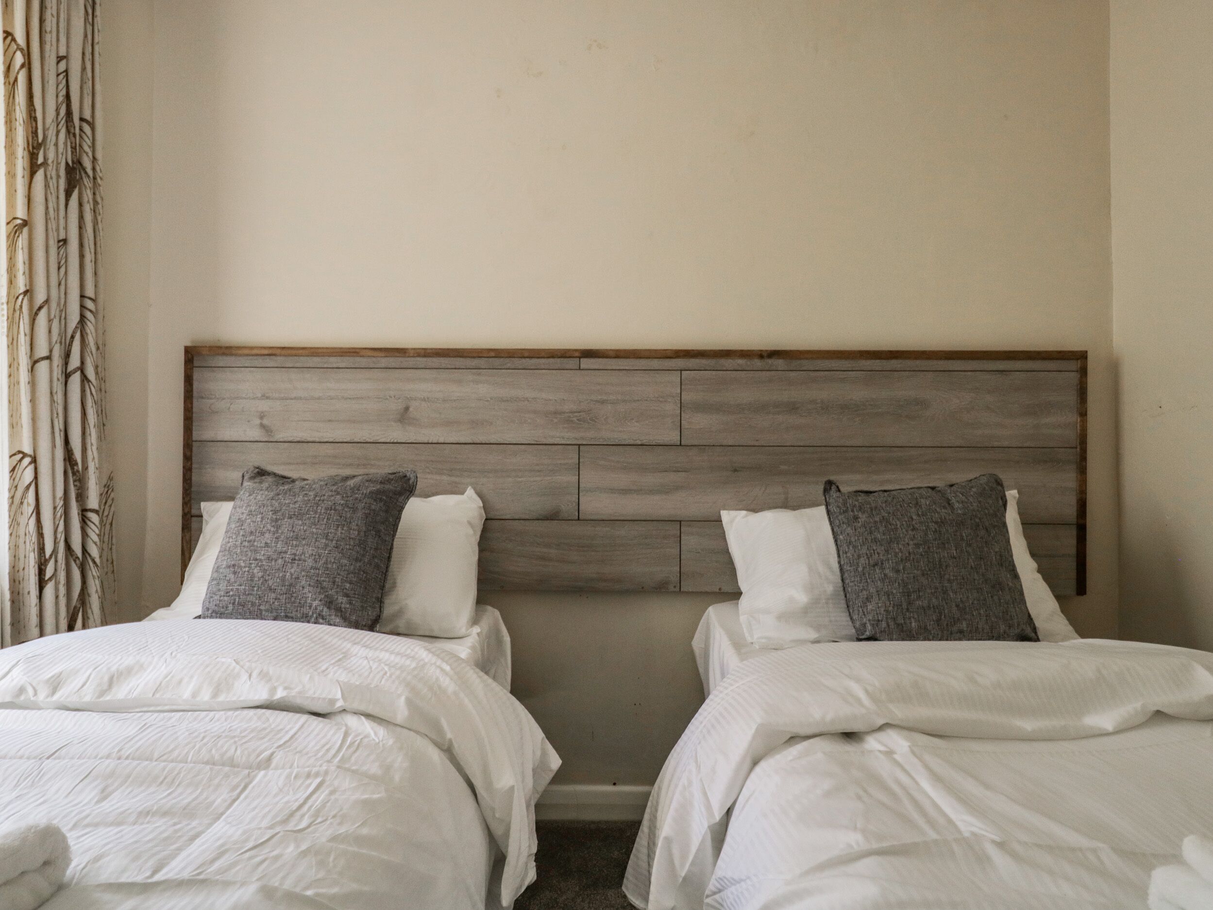 A double bed with a wooden headboard, white bedding, and two pillows.