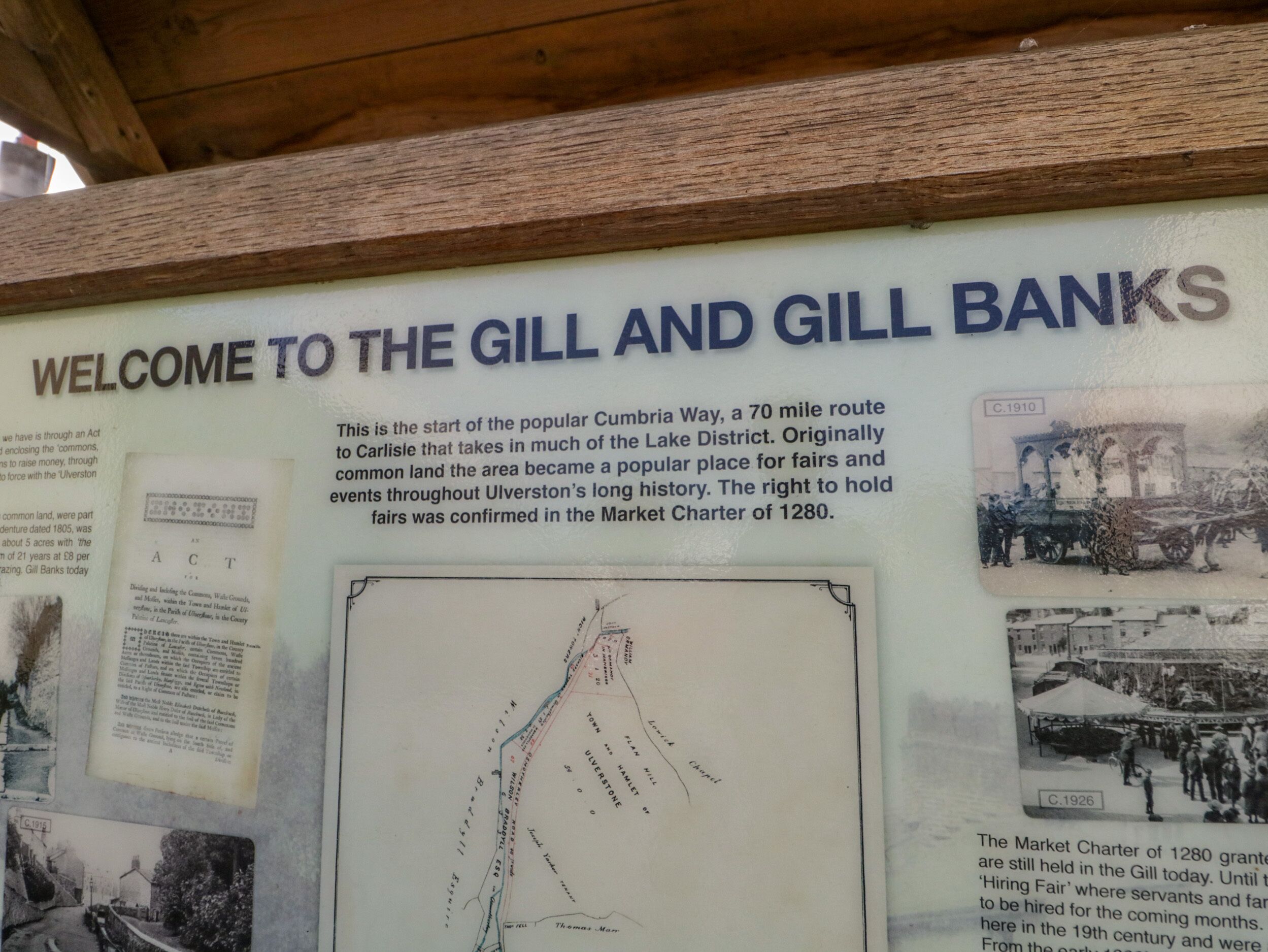 A historical information board at The Gill and Gill Banks, featuring a welcome message, a map, and vintage photographs.