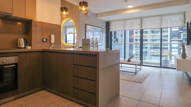 A modern kitchen with wooden cabinets, a built-in oven, and pendant lighting.