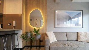 A modern living area with a sofa, a bar stool, a potted plant, and a framed picture on the wall.