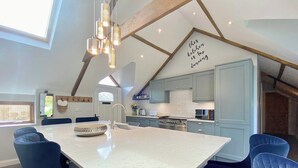 Un'ampia cucina con un'isola grande, elettrodomestici moderni e un design di soffitto originale.