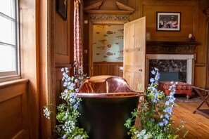 Cozy retreat with a traditional fireplace, wooden paneling, and a beautiful floral arrangement.